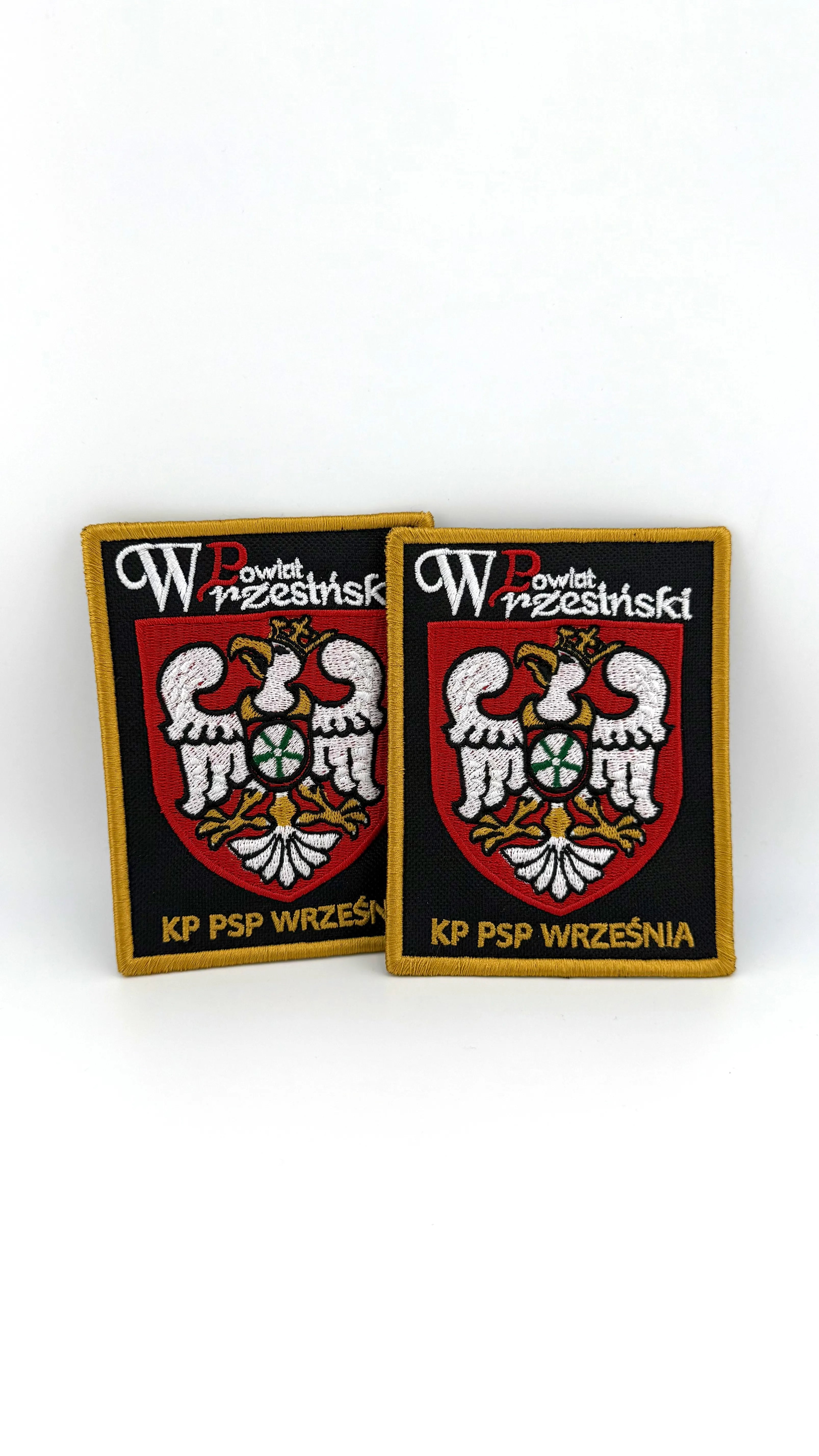 Dwie haftowane naszywki z rzepem z herbem Powiatu Wrzesińskiego i napisem KP PSP WRZEŚNIA - czarne tło, złote obszycie